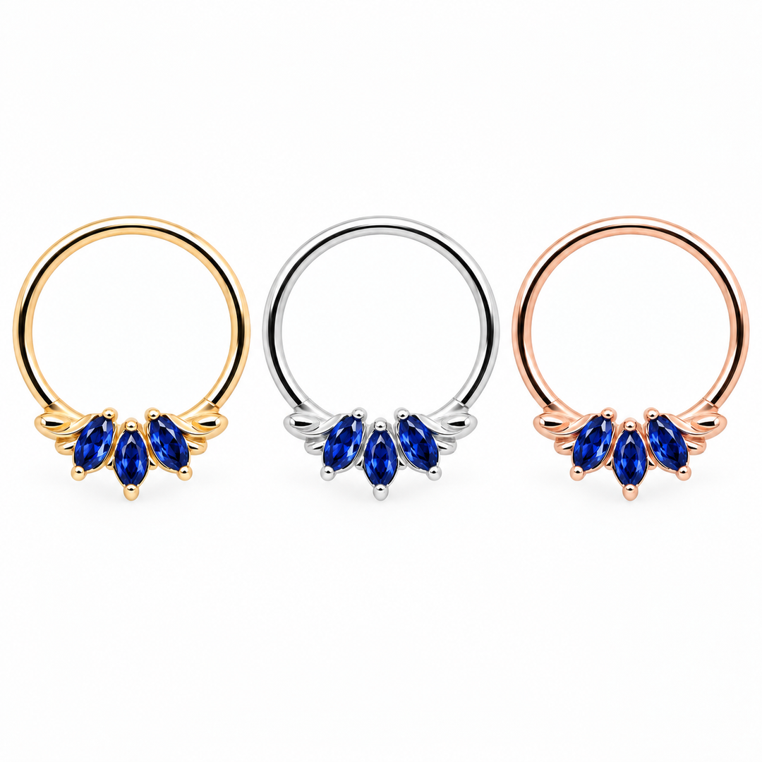 AuAdore Grandeur Lab Blue Sapphire rings in yellow gold, white gold and rose gold from left to right, each with three blue marquise gemstones and smooth hoop tops on white.