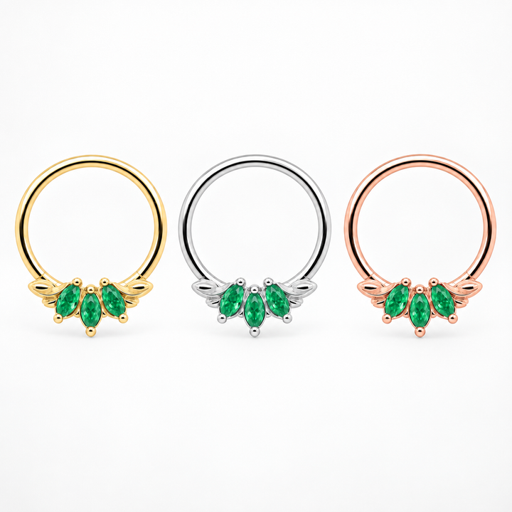 AuAdore Grandeur Natural Emerald piercing rings aligned in one horizontal row, yellow gold, white gold and rose gold from left to right, with matching green marquise gemstones on white.